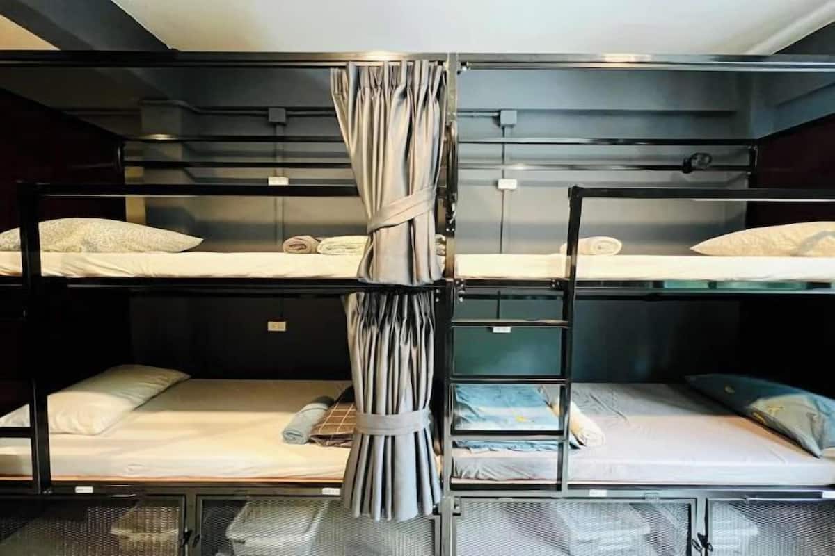 A bunk bed room with a curtain divider, a ladder, and a small table with a chair.