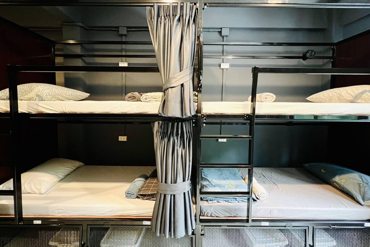 A bunk bed room with three levels, each with a mattress and pillow.