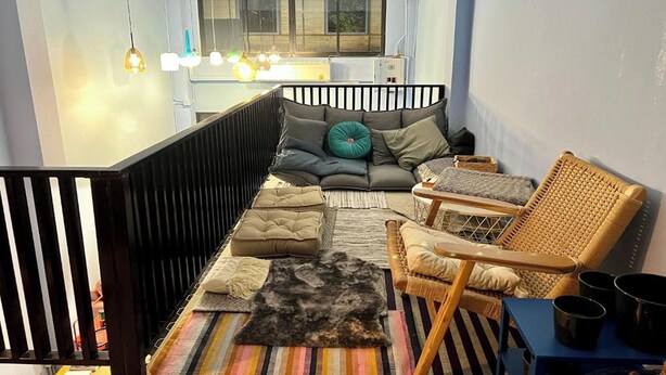 A cozy living area with a sofa, chairs, and a coffee table. There is a window with a view of the outside. - El biografo hostel (Bangkok)