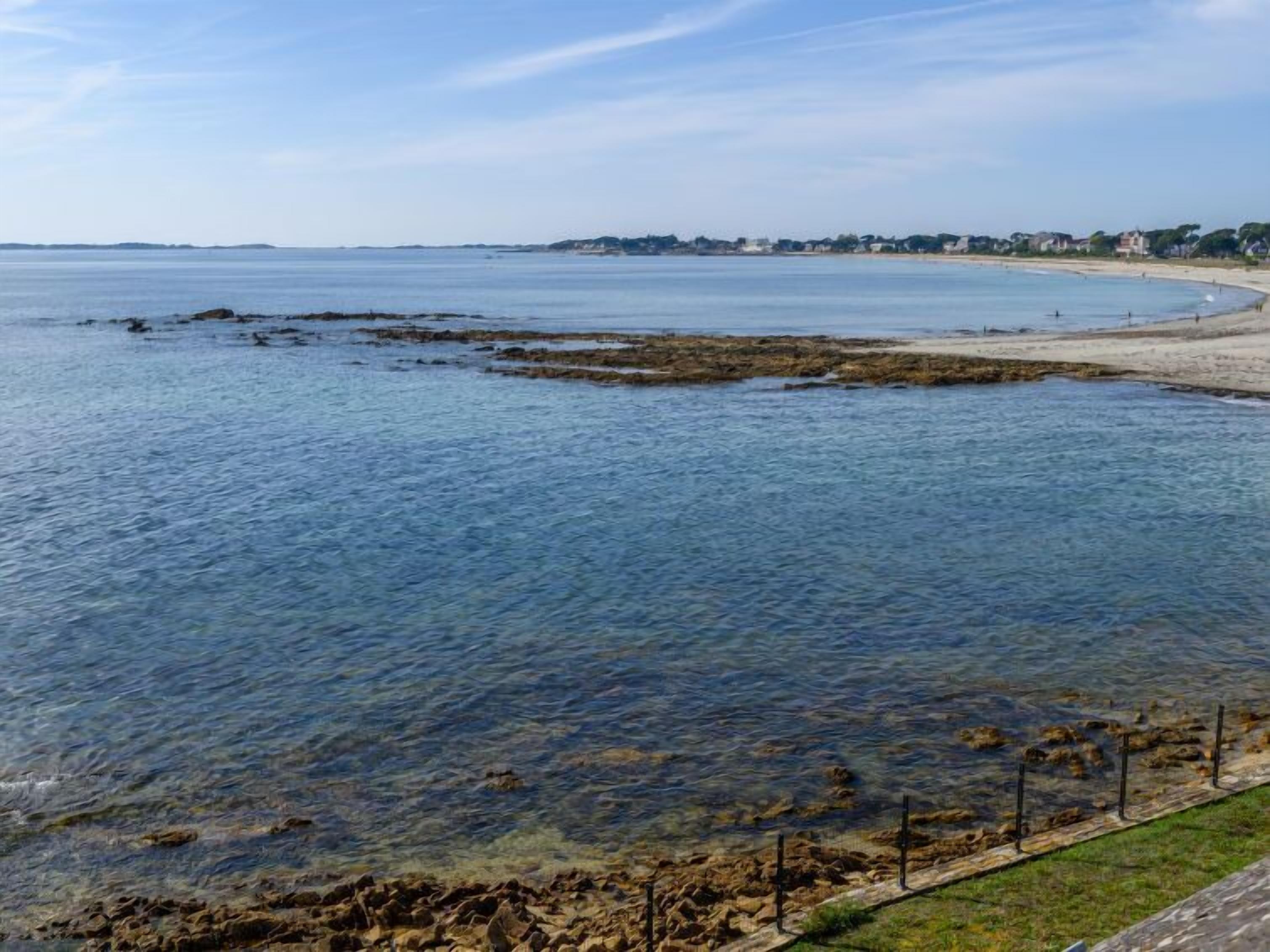 Une vue sur la côte, avec une eau limpide, une plage de sable et une côte rocheuse.