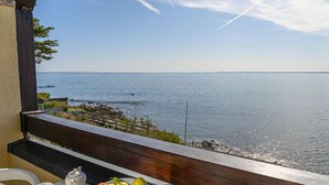 A breakfast table with croissants, fruit, and orange juice on a balcony overlooking a calm sea. - Plein Océan by Interhome (Carnac)