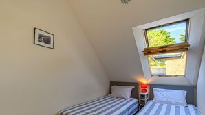 A small, single-room accommodation with two beds, a small table, and a window providing natural light. - Plein Océan by Interhome (Carnac)