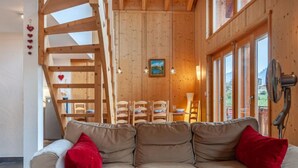 A cozy cabin interior with a sofa, wooden dining table, chairs, and a fan. - Sneachta by Interhome (Nendaz)