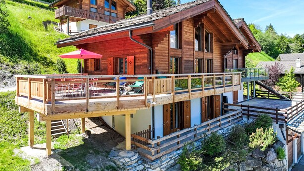A wooden chalet with a balcony and outdoor seating area. - Sneachta by Interhome (Nendaz)