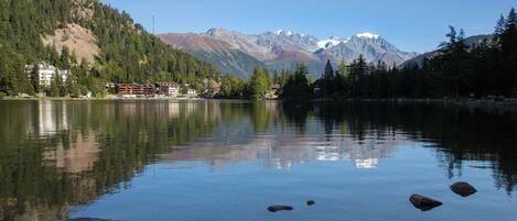 A calm lake with clear reflections of surrounding mountains and trees.