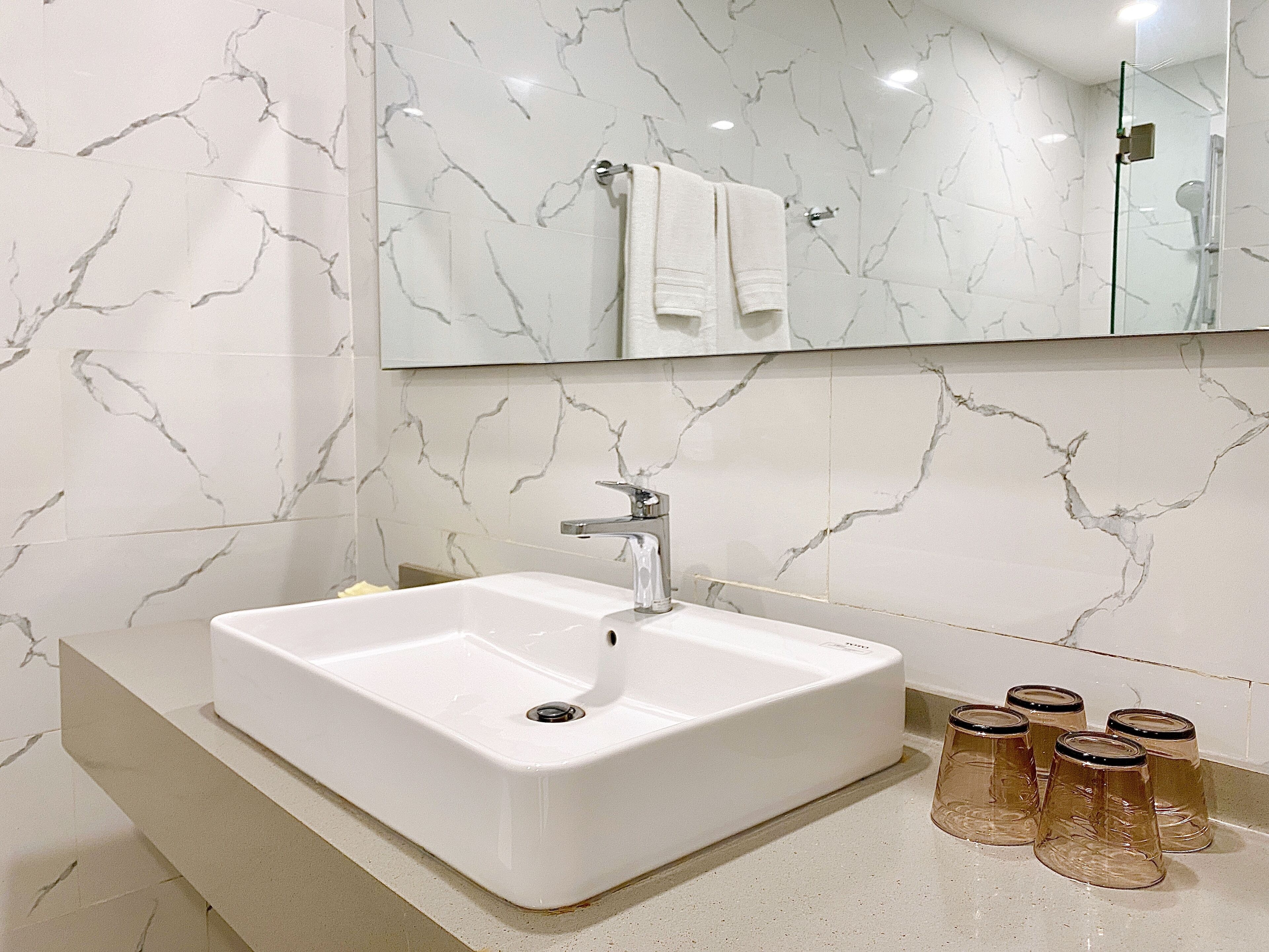 A bathroom with a white sink, a mirror, and a glass shower enclosure.