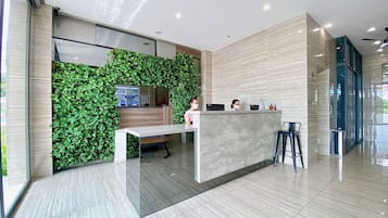 Un espace d’accueil moderne agrémenté d’un mur végétal, d’un comptoir de réception et d’un coin salon.