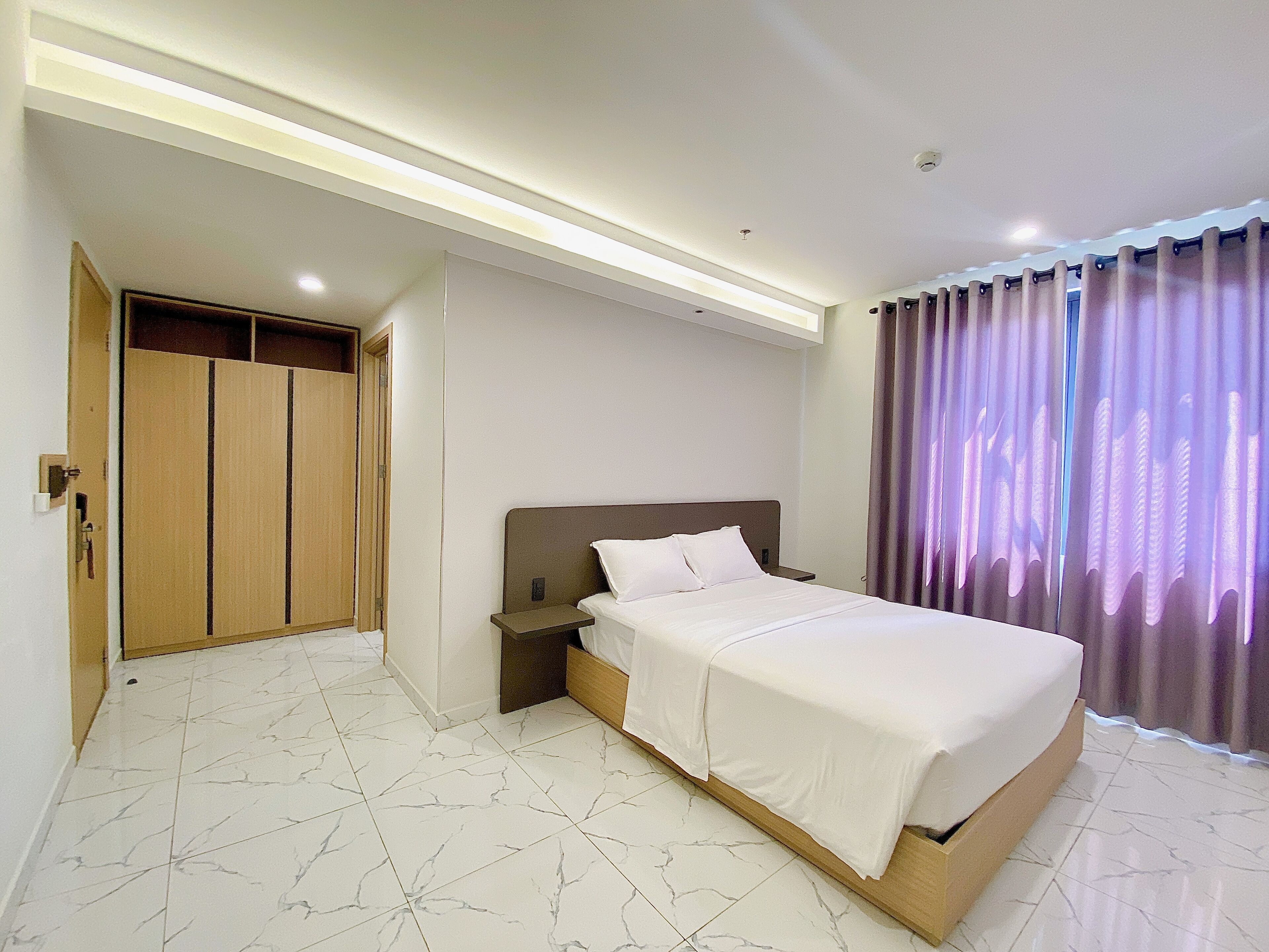 Ein Hotelzimmer mit Bett, Nachttisch, Holzschrank und Badezimmer.