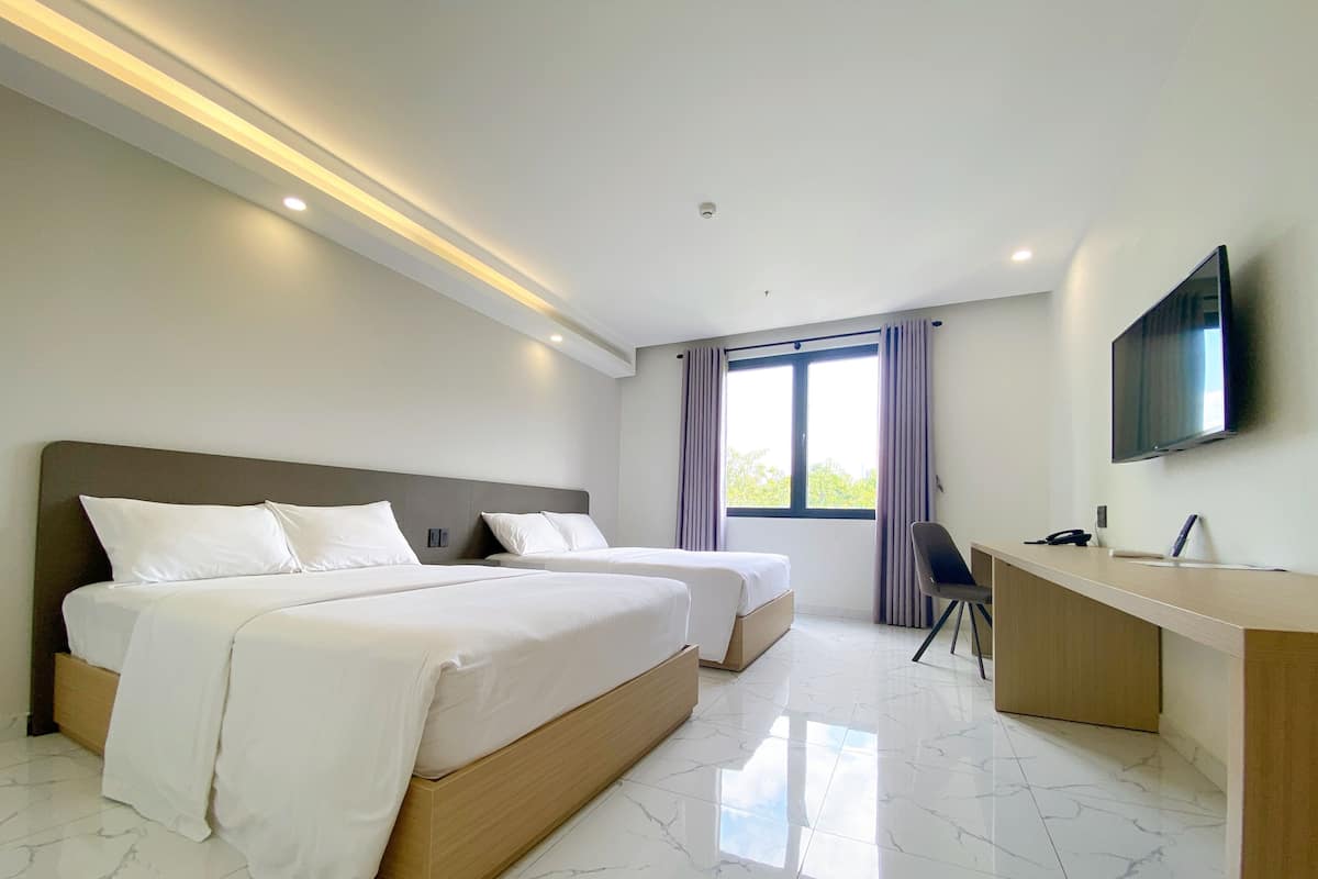 Una habitación de hotel moderna con dos camas, un escritorio y una televisión.