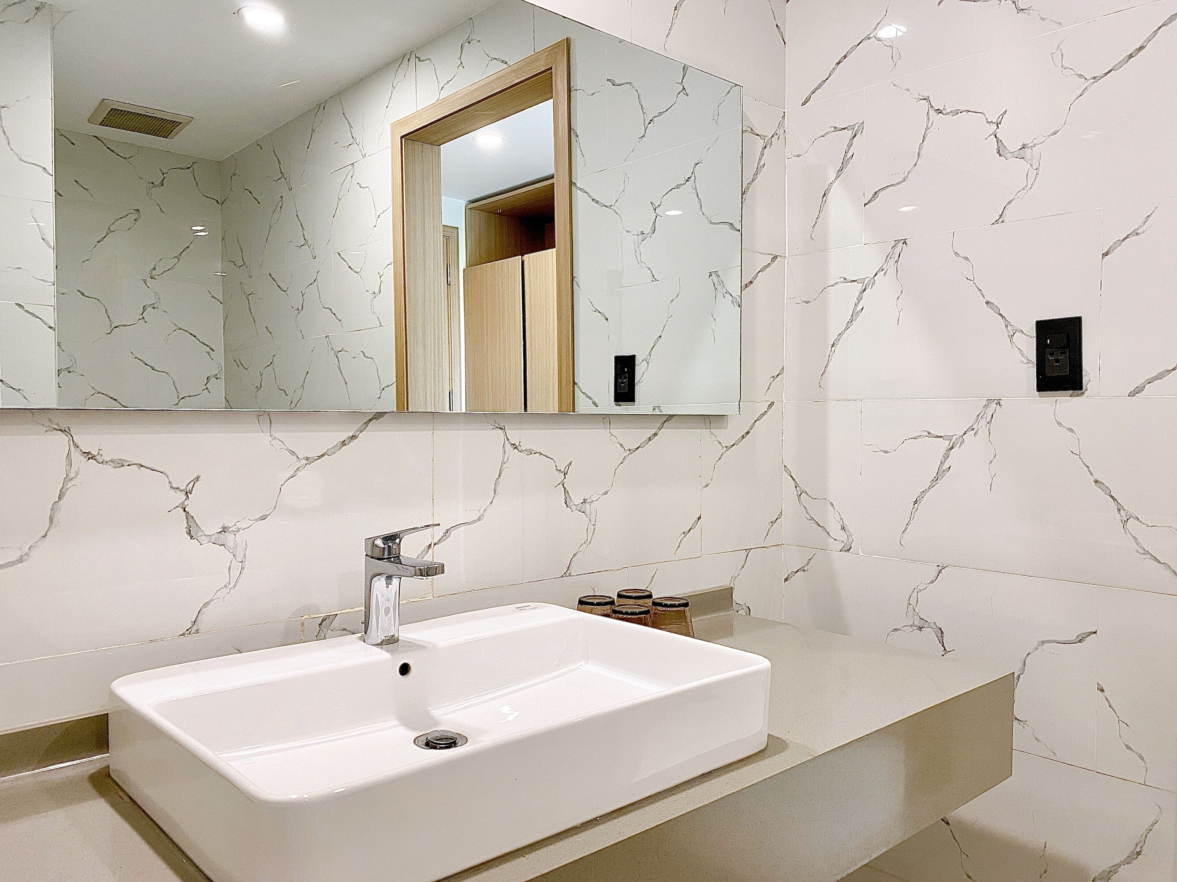 A bathroom with a white sink, a mirror, and marble-patterned walls.