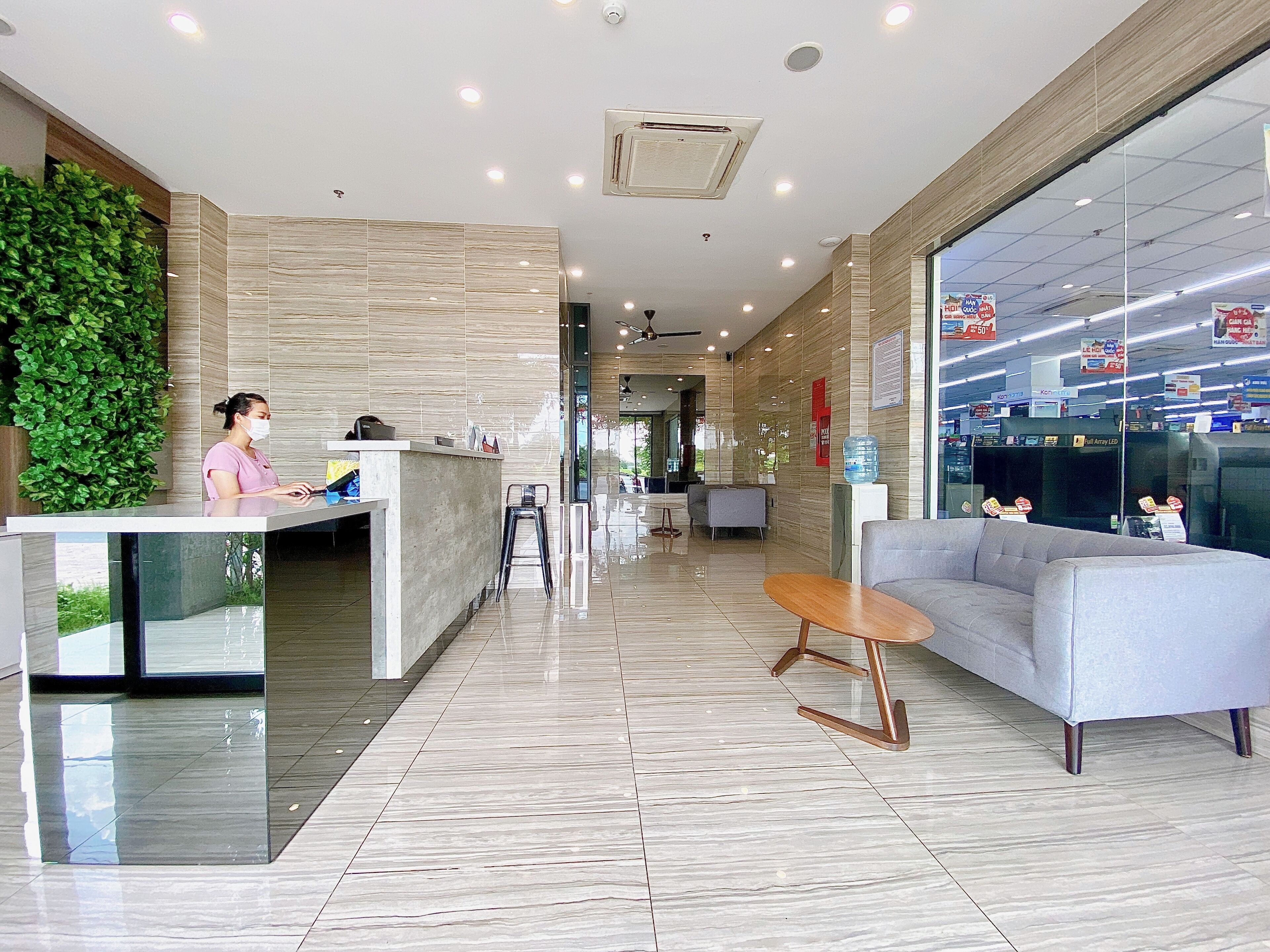 A modern lobby with a reception desk, seating area, and a large window.
