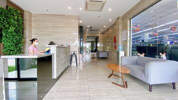 A modern lobby with a reception desk, seating area, and a large window.