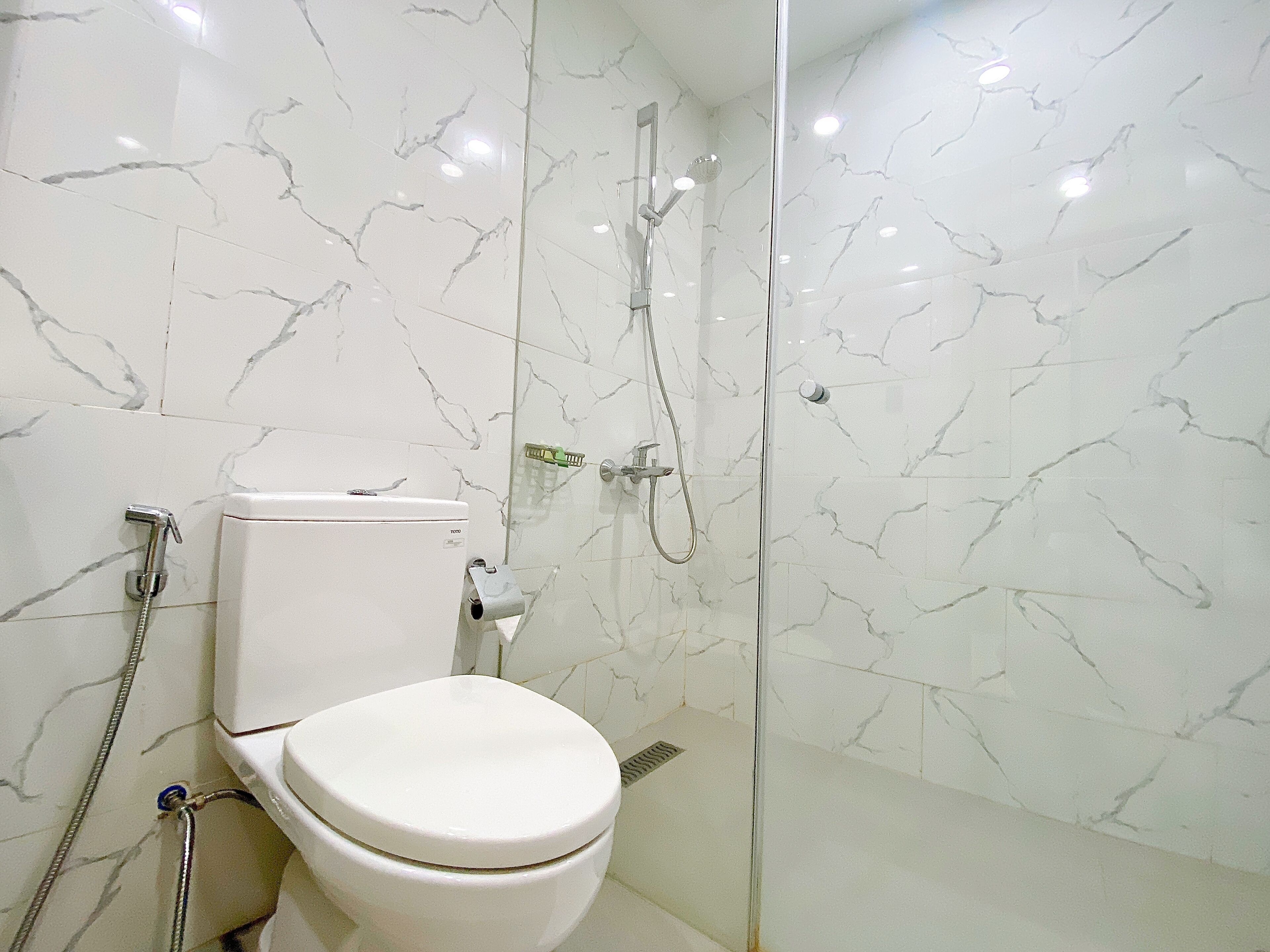 Een moderne badkamer met toilet, douche en douchecabine met glazen wanden.