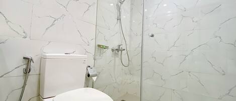 Een moderne badkamer met toilet, douche en douchecabine met glazen wanden.