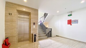 A modern elevator with a control panel, a staircase with black railings, and a fire extinguisher on the floor. - The Luxe Hotel - Chau Doc (Chau Doc)