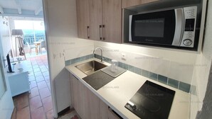 A modern kitchen with a microwave, sink, and stove. - Large mezzanine studio with sea view, parking and AC near the Calanque de la Cron (Cavalaire-sur-Mer)