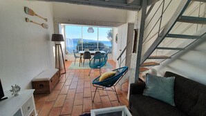 A spacious living area with a terrace, a sofa, a coffee table, and a dining table with chairs. - Large mezzanine studio with sea view, parking and AC near the Calanque de la Cron (Cavalaire-sur-Mer)