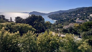 Un paysage côtier offrant une vue sur la mer, des collines et quelques bâtiments dispersés.