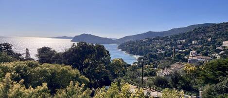 Un paysage côtier offrant une vue sur la mer, des collines et quelques bâtiments dispersés.