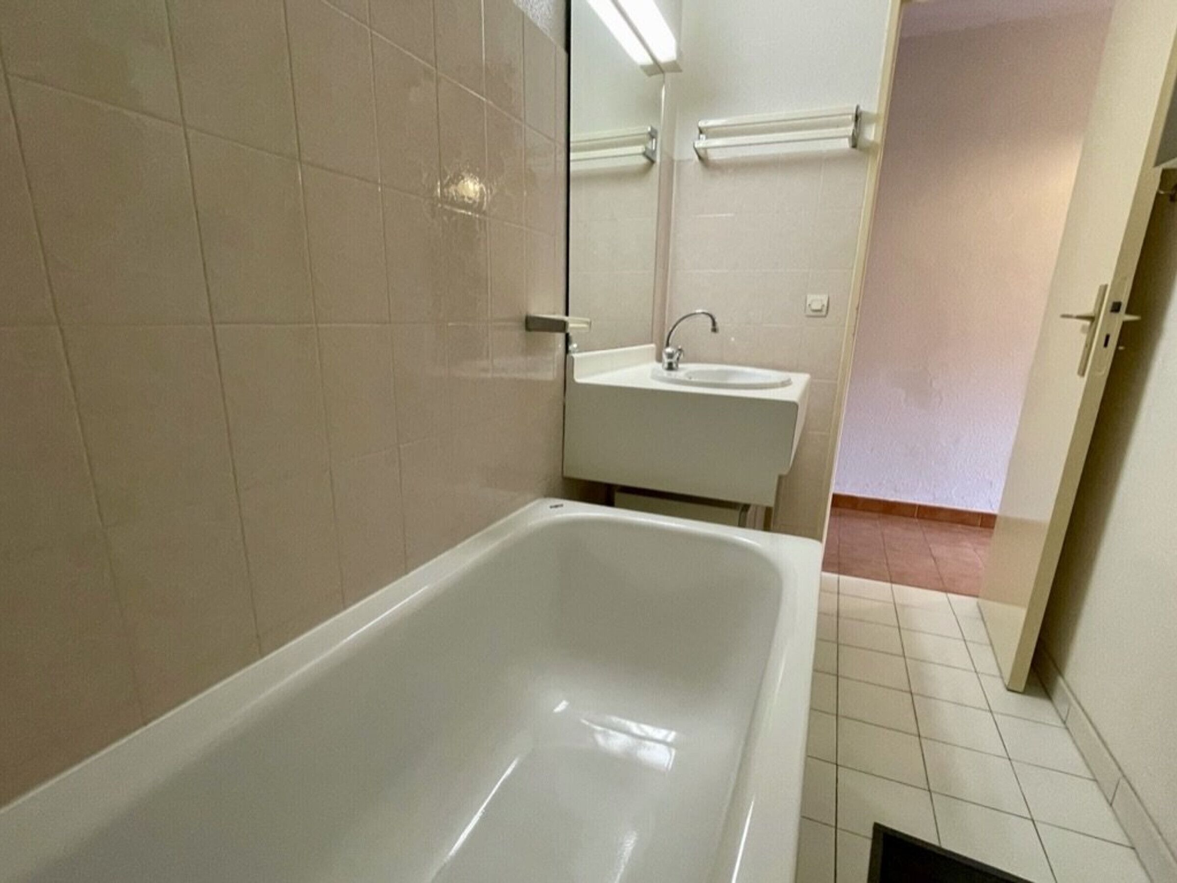 Een badkamer met een bad, een wastafel en een spiegel.