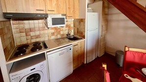 Une cuisine de taille réduite, dotée de meubles en bois, d’un four à micro-ondes, d’un lave-vaisselle et d’une cuisinière.