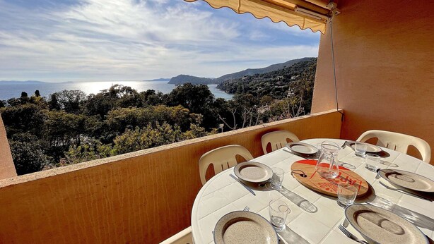 Une table dressée pour deux personnes, avec vue sur la mer et les collines.