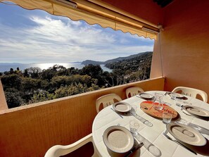 A table set for two with a view of the sea and hills.