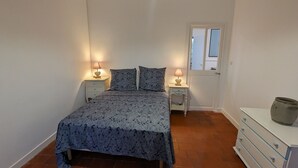 Une chambre à coucher avec un lit, deux tables de chevet avec des lampes, une commode et une fenêtre.