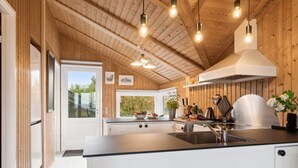 Une cuisine moderne avec des murs en bois, un grand îlot central et des luminaires suspendus.