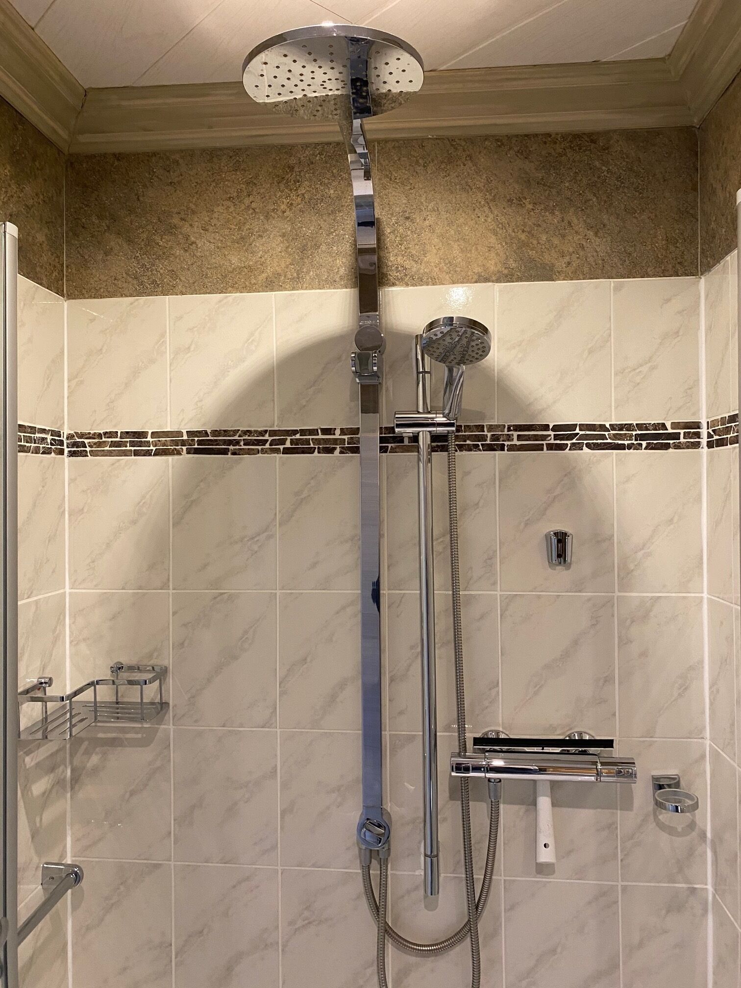 A walk-in shower with a handheld showerhead, a wall-mounted showerhead, and a handheld shower hose.