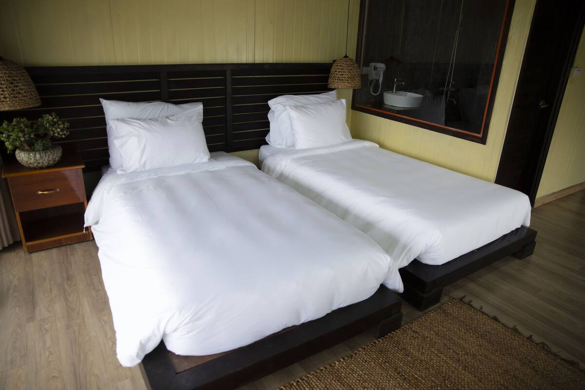 A double bed with white linens in a hotel room.