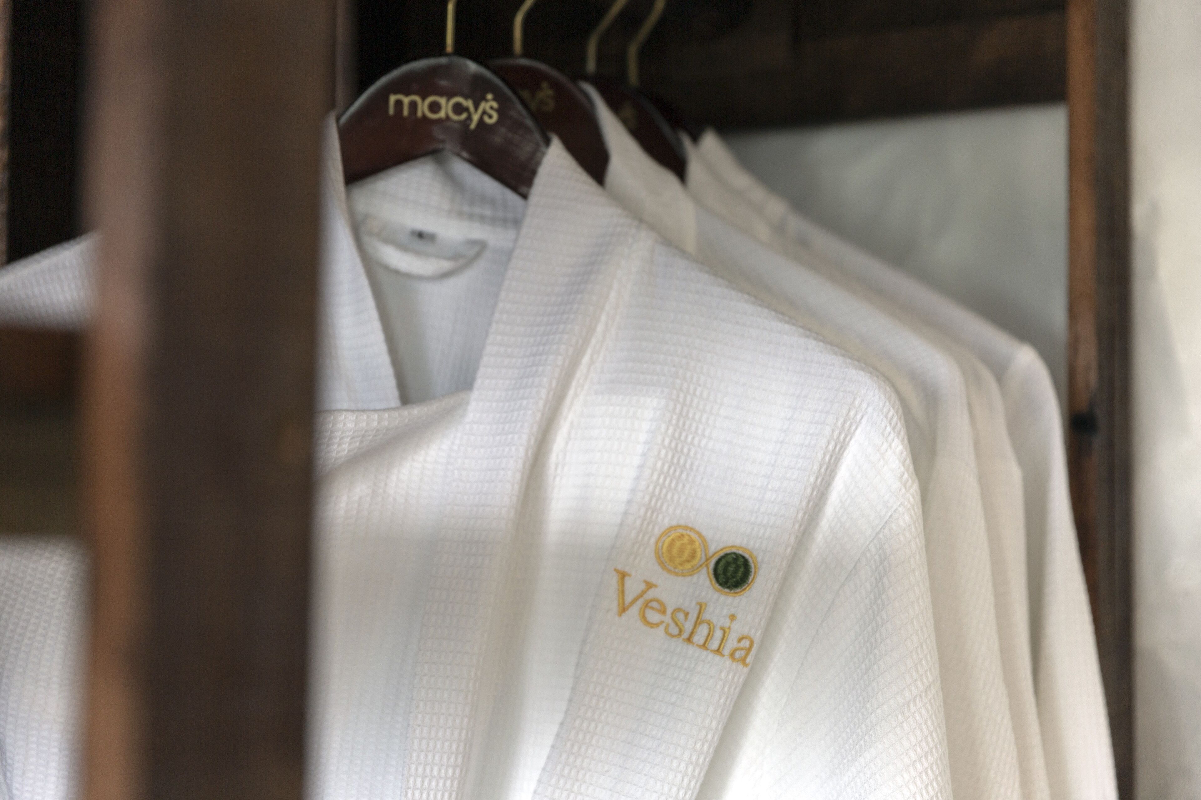 Uma estante com camisas brancas, exibindo um logotipo e texto na parte de trás.
