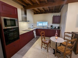 A compact kitchen with a microwave, oven, and a window overlooking the garden.