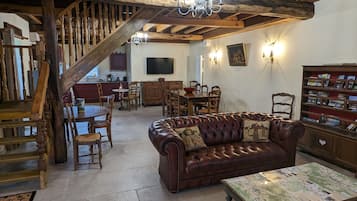 Ein rustikales Interieur mit einer Holztreppe, einem Ledersofa, einem Esstisch und einem Bücherregal.