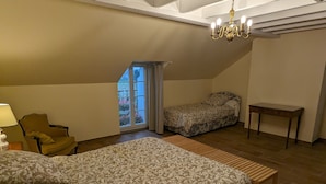 Une chambre à coucher avec un grand lit, une chaise, une petite table et une fenêtre avec des rideaux.