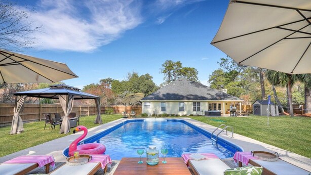A backyard with a swimming pool, lounge chairs, and umbrellas. - Savannah 5BR Pool, Jacuzzi, Firepit, Sports, Games (Savannah)