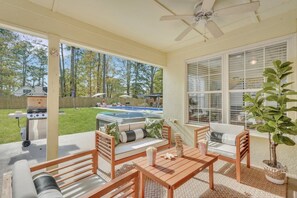 A covered patio with outdoor furniture, a hot tub, and a barbecue grill.