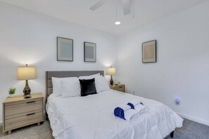 A hotel room with a bed, two bedside tables, and wall-mounted lamps.