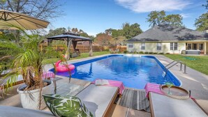 A backyard with a swimming pool, lounge chairs, and a covered patio area. - Savannah 5BR Pool, Jacuzzi, Firepit, Sports, Games (Savannah)