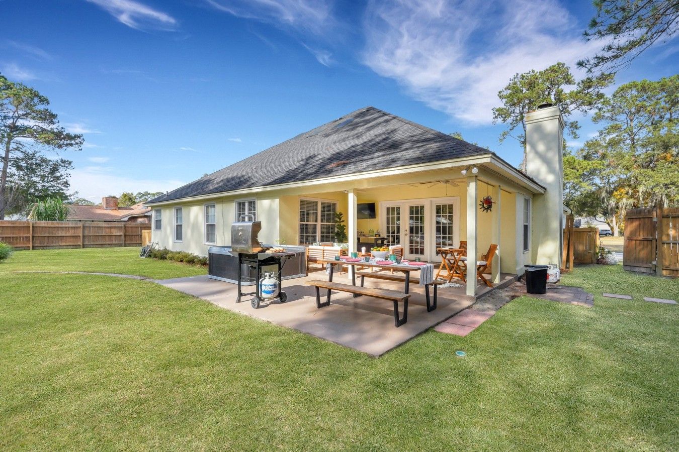 A residential house with a covered patio, a barbecue grill, and a lawn.