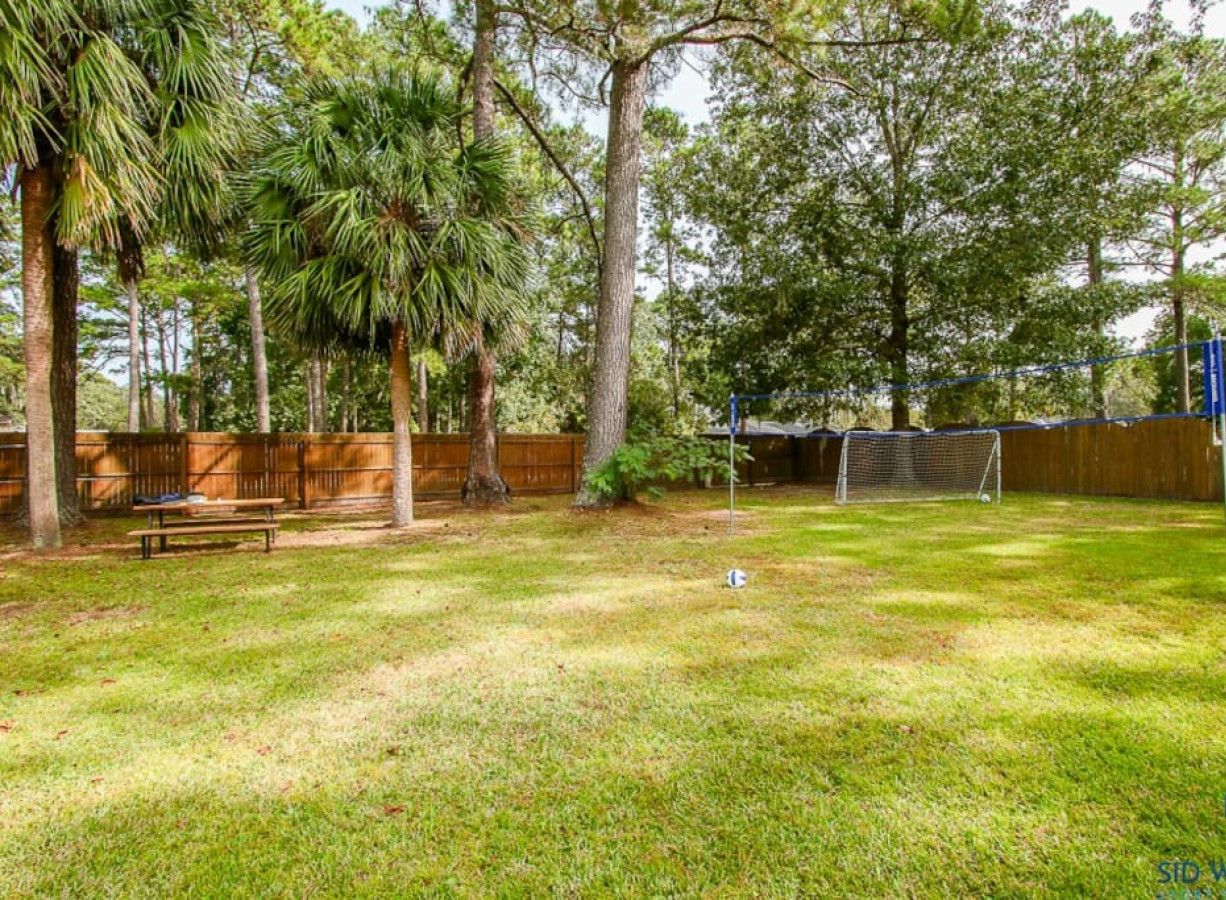 A backyard with a wooden fence, a picnic table, and a soccer goal.