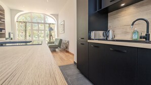 A modern kitchen with dark cabinets, a wooden countertop, and a stainless steel toaster. - Ground Floor Apartment in Historic Setting, Near Downtown Châteauroux (Châteauroux)