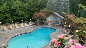 A swimming pool with a curved edge, surrounded by lounge chairs and a small building. - 3BR Condo Retreat w/ Seasonal Pool & Hot Tub, Balcony, Views & Near Ober Mtn (Gatlinburg)