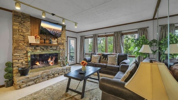 A living room with a stone fireplace, a sofa set, a coffee table, and a lamp. - 3BR Condo Retreat w/ Seasonal Pool & Hot Tub, Balcony, Views & Near Ober Mtn (Gatlinburg)