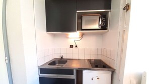 Een kleine keuken met een spoelbak, een magnetron en een koelkast.