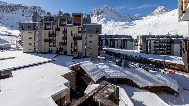 Un hôtel moderne à plusieurs étages, doté de balcons, entouré d’un paysage enneigé et offrant une vue sur les montagnes.