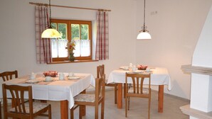 A dining area with two tables, chairs, and hanging lamps. - Holzhammer Hof (Bayerbach)