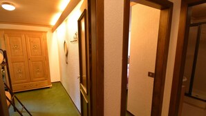 A hallway with a green carpet, wooden doors, and a wooden cabinet with floral designs.