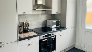 Een moderne keuken met witte kasten, een zwart aanrecht, een magnetron, een oven en een afzuigkap.