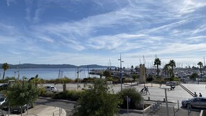 A marina with boats, a clear sky, and a distant mountain range.